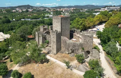 Imagem de um castelo medieval no meio de uma cidade rodeado de árvores, o castelo de Guimarães. Crédito: Shutterstock