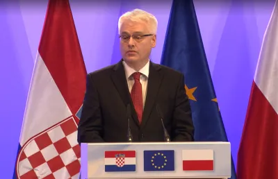 Um homem de cabelo branco fala num púlpito, com as bandeiras da Croácia e da União Europeia atrás.  © European Union