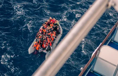 Um barco de borracha cheio de migrantes no meio do oceano. Crédito: Shutterstock