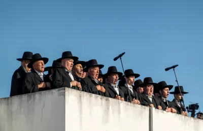 Um grupo de homens de samarra alentejana cantam ao microfone. Crédito: Shutterstock