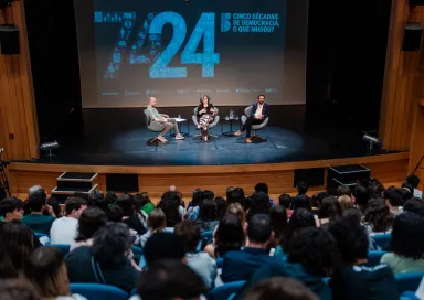 Imagem do auditório da Escola Secundária de Camões, em Lisboa, com Hugo van der Ding a moderar a conversa entre os alunos, Mónica Vieira, e o economista Pedro Freitas