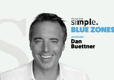 Retrato a preto e branco de Dan Buettner, com texto "BLUE ZONES" ao lado.