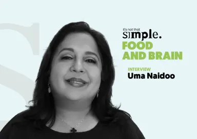 Retrato a preto e branco da psiquiatra nutricional Uma Naidoo sobre um fundo azul claro. Texto: "It's not that simple. Food and Brain. Interview".
