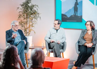 Uma plateia sentada a ouvir um debate entre quatro pessoas que estão em palco.