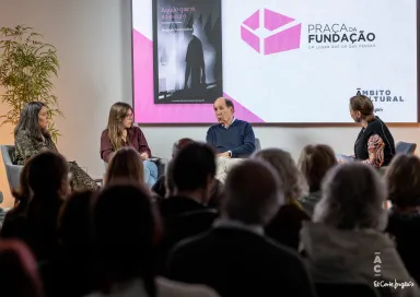 Quatro pessoas sentadas em palco a debater. Ao fundo, uma tela com a capa do livro da Fundação «Aquilo que Vi no Escuro, Histórias sobre a psicose».