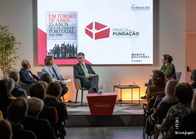 Quatro pessoas sentadas num palco. Atrás, um ecrã com a capa de um livro da Fundação e com o texto "Praça da Fundação".