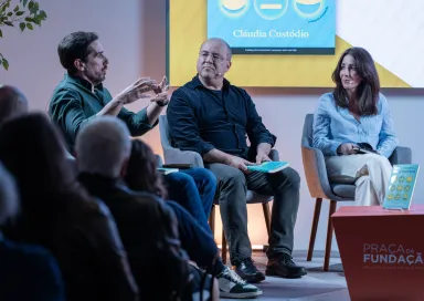 Uma plateia a assistir a um debate entre os humoristas Cláudio Almeida, Nuno Artur Silva e a economista Cláudia Custódio.