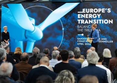 Uma plateia de costas a assistir à apresentação de duas mulheres, num palco. Texto "Europe's Energy Transition".
