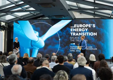 Uma plateia de costas a assistir à apresentação de duas mulheres, num palco. Texto "Europe's Energy Transition".