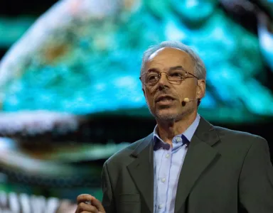 O ecologista e escritor Carl Safina a discursar sobre um fundo colorido de um ambiente marinho.