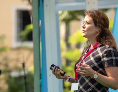 A economista Martha Bailey a discursar, de pé, com um jardim de fundo.