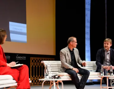 Painel de discussão com três pessoas.