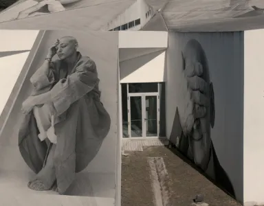 Imagens em preto e branco de pessoas em murais num edifício moderno.