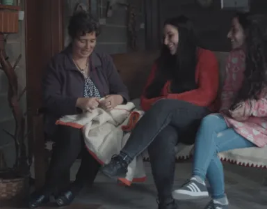 Uma mãe a conversar com as filhas adolescentes enquanto costura.