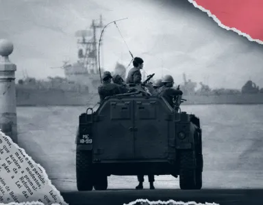 Soldados num veículo militar com o número «ME-18-99», durante a Revolução dos Cravos. Ao fundo, um navio. Ambiente cinza. ©Alfredo Cunha, SPA 2024