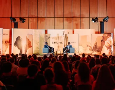 Um evento com um público sentado, duas pessoas em palco, uma delas o sociólogo Hein de Haas.