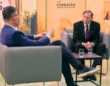 David Petraeus sentado, à frente de um jornalista, a ser entrevistado em Lisboa