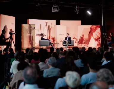 Evento com público sentado, e Peter Frankopan, em palco, a ser entrevistado por um jornalista. 