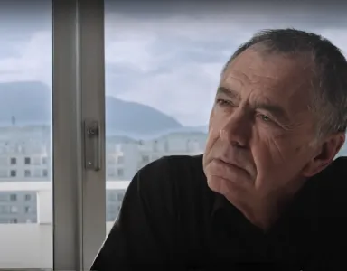 O filósofo e sociólogo Gilles Lipovetsky com ar pensativo, junto a uma janela com montanhas ao fundo.