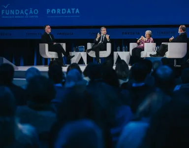 Debate em palco com quatro pessoas sentadas, atrás de uma plateia, com os logos da Fundação e da Pordata.