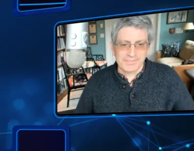 Uma tela que projeta Carl Zimmer, com o cabelo grisalho, a usar uma camisola escura, sentado.