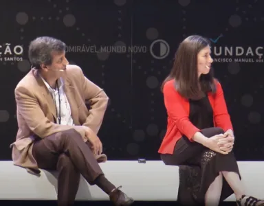 Ellen Jorgensen e o professor Pedro Lima sentados num banco branco. Texto: Admirável Mundo Novo" e logotipo da Fundação ao fundo.