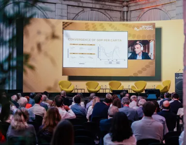 Conferência com várias pessoas a olhar para uma tela com Thomas Philippon.
