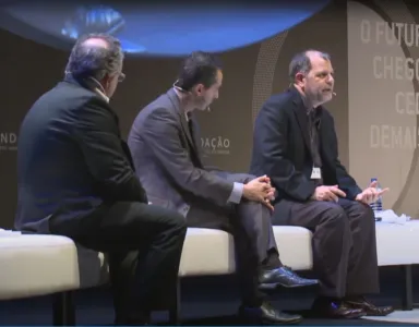 O economista Tyler Cowen a discursar, sentado num sofá branco, ao lado de dois homens. Fundo cinzento, com o logotipo da Fundação e com o texto: "O futuro chegou cedo demais?".