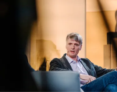 Neil Lawrence sentado numa cadeira, vestido com um blazer preto e uma camisa clara, a falar, durante um evento da Fundação.