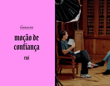 Guilherme Geirinhas sentado ao lado de Rui Tavares. Texto "moção de confiança" sobre um fundo rosa.