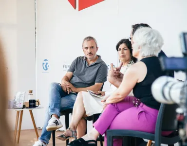Quatro pessoas debatem durante um evento da Fundação. Ao fundo, uma mesa com canecas e livros expostos.