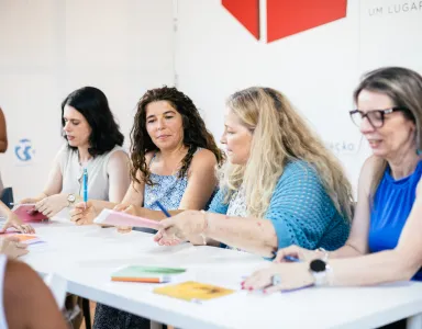 Quatro mulheres sentadas numa mesa, a interagir enquanto assinam livros.