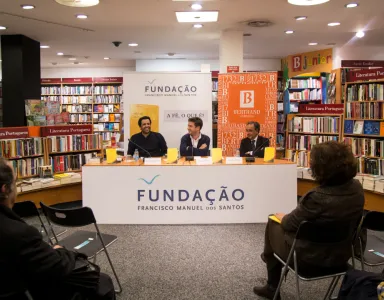 Apresentação de um livro numa livraria, com três oradores e banners da Fundação.