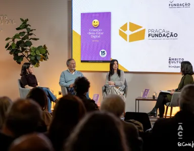 Quatro pessoas sentadas no palco, com uma plateia a assistir, e um ecrã que tem a capa de um livro da Fundação.