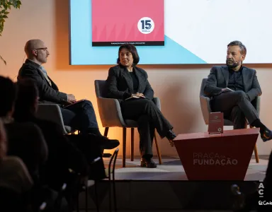 Dois homens e uma mulher sentados, em palco, à conversa sobre o livro da Fundação, que está pousado numa mesa entre eles