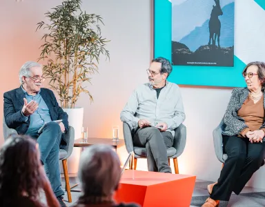 Uma plateia sentada a ouvir um debate entre quatro pessoas que estão em palco.