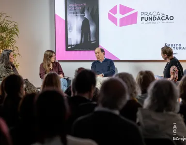 Quatro pessoas sentadas em palco a debater. Ao fundo, uma tela com a capa do livro da Fundação «Aquilo que Vi no Escuro, Histórias sobre a psicose».