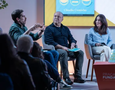 Uma plateia a assistir a um debate entre os humoristas Cláudio Almeida, Nuno Artur Silva e a economista Cláudia Custódio.