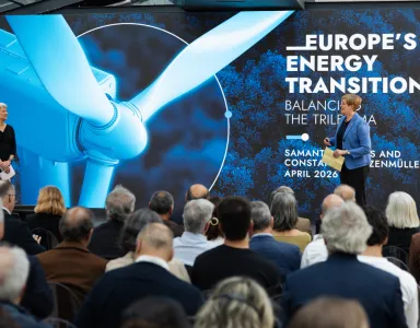 Uma plateia de costas a assistir à apresentação de duas mulheres, num palco. Texto "Europe's Energy Transition".
