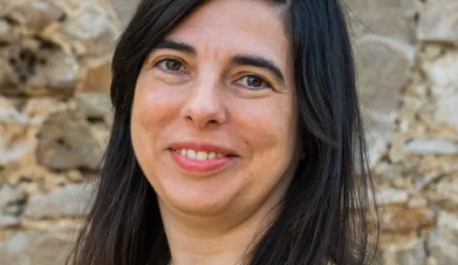 Retrato da professora e investigadora Ioli Campos, sobre uma parede de pedra.