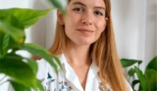 A jovem jornalista húngara, Lili Rutai, sentada tendo uma parede branca como fundo. Crédito: Lili Rutai 