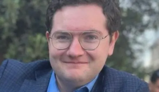 Retrato a cores do analista Decker Eveleth, num fundo com vegetação.