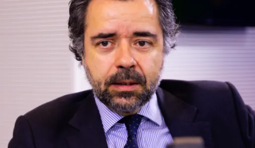 Imagem de um homem sentado, num estúdio de rádio, com um microfone à frente.