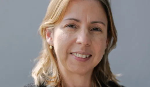 Uma mulher loira, sorridente, com um colar ao pescoço. D/R.