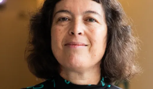 Retrato da psiquiatra Manuela Silva a sorrir. Fundo amarelo.