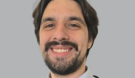 Imagem de um rapaz sorridente, vestido com um polo e uma camisa. Fundo conzento.