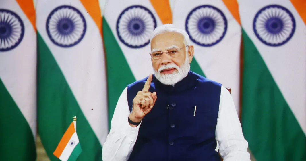 O primeiro-ministro da Índia Narendra Modi tendo como fundo um conjunto de bandeiras do país. Crédito: Shutterstock