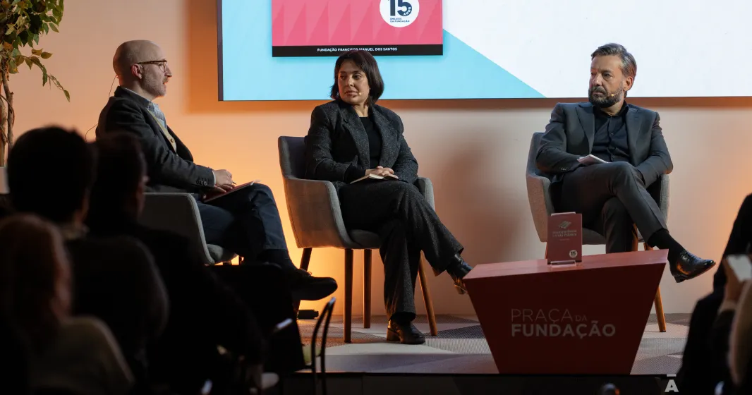 Dois homens e uma mulher sentados, em palco, à conversa sobre o livro da Fundação, que está pousado numa mesa entre eles