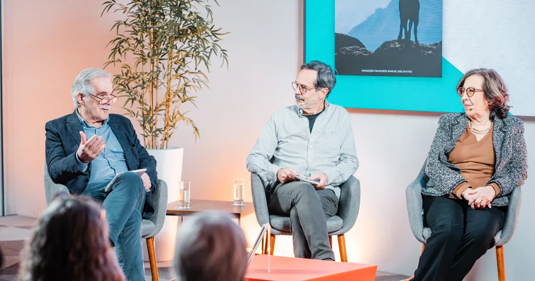 Uma plateia sentada a ouvir um debate entre quatro pessoas que estão em palco.