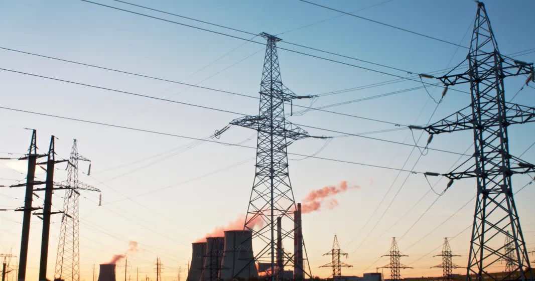 Uma paisagem com torres de refrigeração e uma central elétrica, tendo como fundo um céu azul. Crédito: Shutterstock
